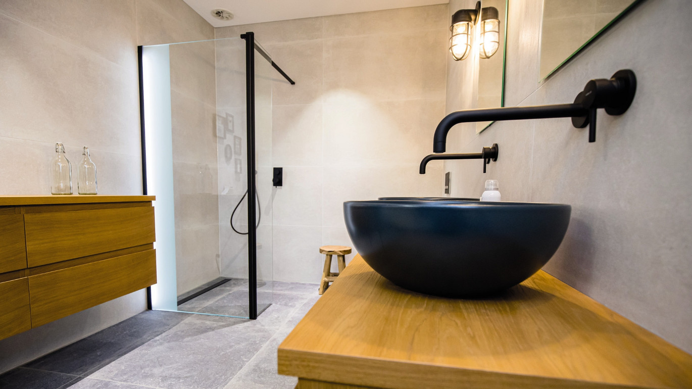 Skats uz Showerdrain Black, fonā arī melna izlietne uz dabīgas koka virsmas.